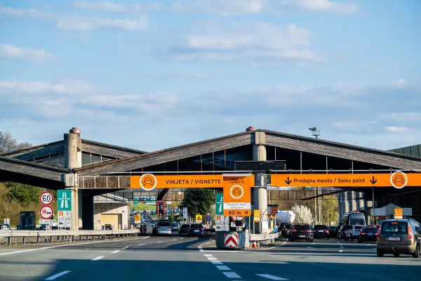 Slovenia orange Vinjeta Vignette and Prodajno Mesto sales point gantry at border crossing with heavy traffic queuing and sales point 80m ahead sign visible, April 2026